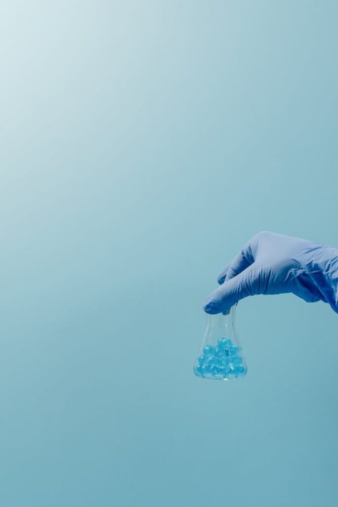 pexels-photo-7722597 A Hand Wearing Gloves Holding a Glassware with Small Blue Balls